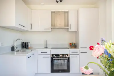 a white kitchen with white cabinets and an oven at Mereveld Studios in Utrecht