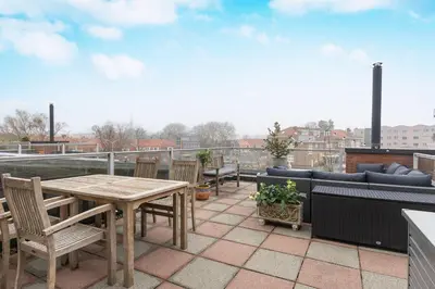 a patio with a table and chairs on a roof at Zaan City Deck in Zaandam
