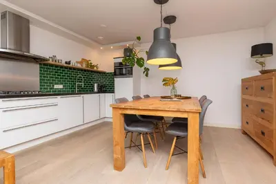 a kitchen with a wooden table and chairs at Zaan City Deck in Zaandam