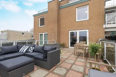 a patio with a couch and a table on a balcony at Zaan City Deck in Zaandam