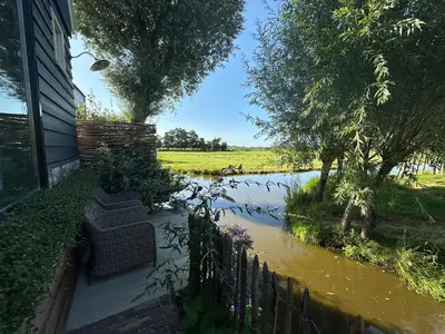 a flooded backyard with a house and a river at B&B De Wilgenhoeve in Kwadijk