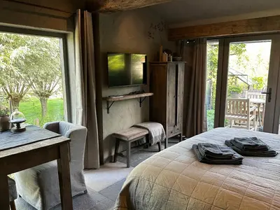 a bedroom with a bed and a table and a window at B&B De Wilgenhoeve in Kwadijk