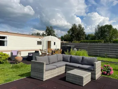 a patio with a couch and an umbrella at Houseboatvinkeveen Lelie in Vinkeveen