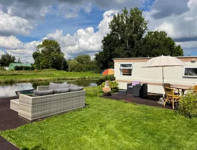 a caravan with a couch and an umbrella and a table at Houseboatvinkeveen Lelie in Vinkeveen