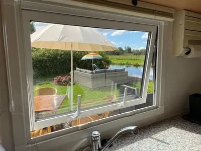 a window with a view of a patio with an umbrella at Houseboatvinkeveen Lelie in Vinkeveen
