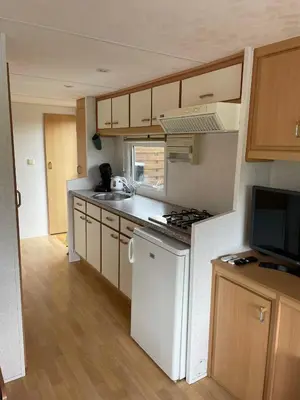 a small kitchen with white appliances and wooden cabinets at Houseboatvinkeveen Lelie in Vinkeveen