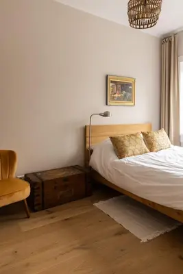 a bedroom with a bed and a chair and a lamp at Zandhuys in Zandvoort