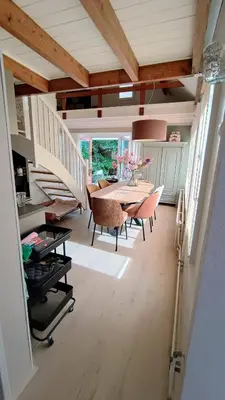 a dining room with a table and a staircase at Vakantiehuis Lycka in Noordwijkerhout