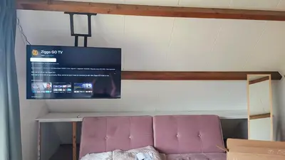 a room with a purple couch and a tv on the wall at Vakantiehuis Lycka in Noordwijkerhout