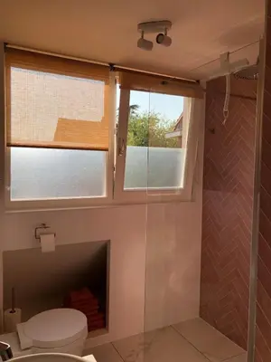 a bathroom with a toilet and a glass shower at Appartement Buissant des Amorie! in Castricum