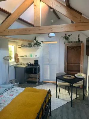 a bedroom with a bed and a table and a kitchen at Little Betsy in Zandvoort