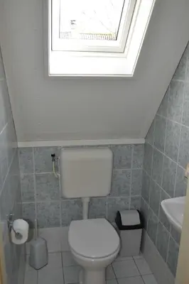 a bathroom with a white toilet and a window at Ankes Traumhaus in Sint Maarten