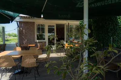 a patio with a table and chairs and an umbrella at Hotel Zuideinde in Nieuwkoop
