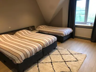 two twin beds in a room with a rug at Hotel Zuideinde in Nieuwkoop