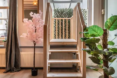 a wooden staircase in a room with a pink tree at Cozy two-room city center apartment with garden in Amersfoort