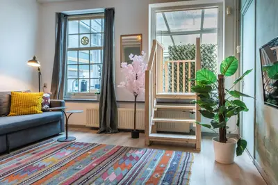 a living room with a blue couch and a plant at Cozy two-room city center apartment with garden in Amersfoort