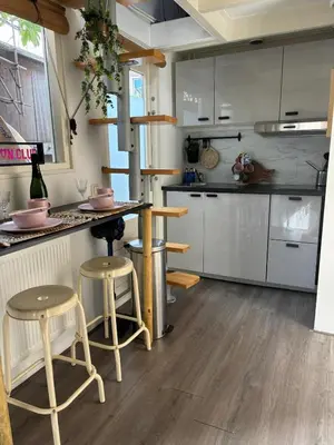 a kitchen with white cabinets and a counter with stools at Tiny House - Surfers Paradise in Noordwijk