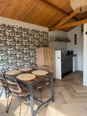 a table and chairs in a room with a stone wall at 't Hoevehuisje in Beverwijk
