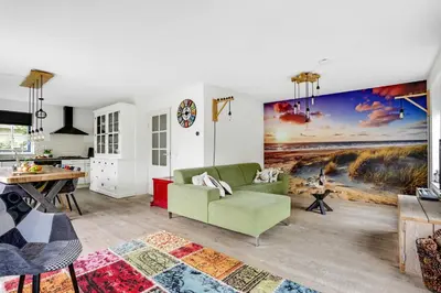a living room with a green couch and a painting on the wall at Vakantiepark Schoorlse Duinen in Schoorl