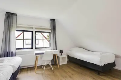 a bedroom with two beds and a desk and a window at Vakantiepark Schoorlse Duinen in Schoorl