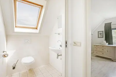 a bathroom with a toilet and a sink and a window at Vakantiepark Schoorlse Duinen in Schoorl