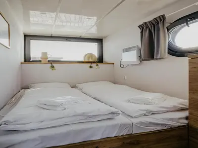 two beds in a small room with a window at Houseboat at Marina with Lake Views in Uitgeest