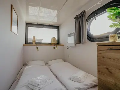 a bed in a small room with a window at Houseboat at Marina with Lake Views in Uitgeest