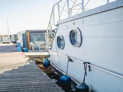a boat is parked next to a dock at Houseboat at Marina with Lake Views in Uitgeest