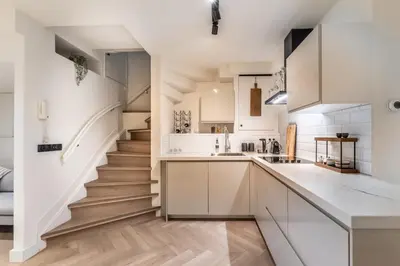 a kitchen with white cabinets and a staircase at Central Luxury Apartment in Amsterdam