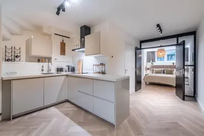 a kitchen with white cabinets and a living room at Central Luxury Apartment in Amsterdam