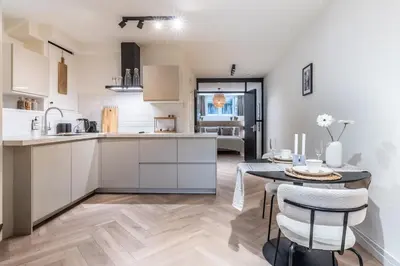 a kitchen with white cabinets and a table with chairs at Central Luxury Apartment in Amsterdam