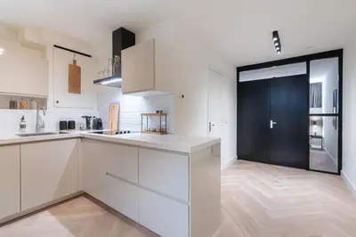 a kitchen with white cabinets and a black door at Central Luxury Apartment in Amsterdam