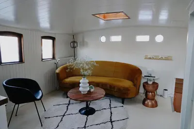 a living room with a couch and a table at City center Amstel river Houseboat Kom en Zie in Amsterdam
