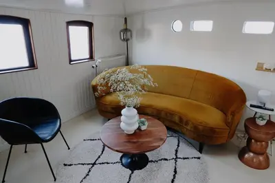 a living room with a couch and a table at City center Amstel river Houseboat Kom en Zie in Amsterdam