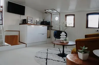 a living room with a tv and a chair and a table at City center Amstel river Houseboat Kom en Zie in Amsterdam