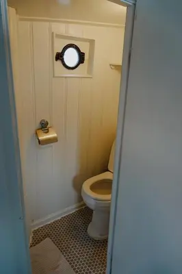 a small bathroom with a toilet with a window at City center Amstel river Houseboat Kom en Zie in Amsterdam