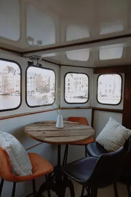 a table in the back of a boat with windows at City center Amstel river Houseboat Kom en Zie in Amsterdam