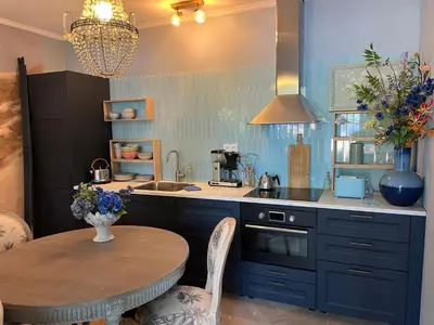 a kitchen with blue cabinets and a table and a sink at Strandrit in Groet