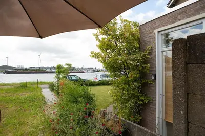 a house with an umbrella and a view of the water at Hemhuisje in Zaandam