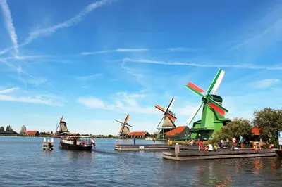 a group of windmills on the water with a boat at Hemhuisje in Zaandam