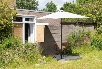 a chair and an umbrella in front of a house at Hemhuisje in Zaandam