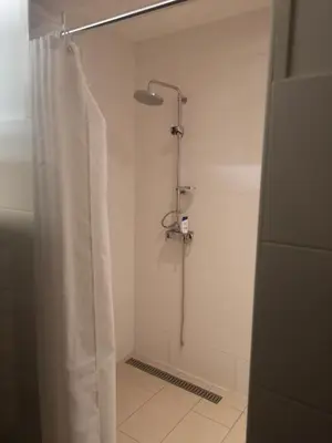 a shower with a white shower curtain in a bathroom at Sweet Treehouse in Westbeemster