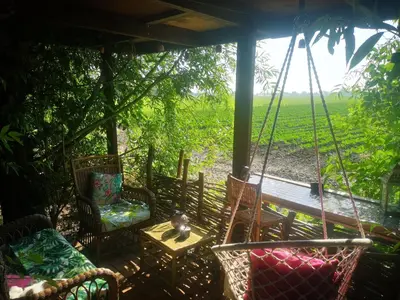 a porch with chairs and a table and a swing at Sweet Treehouse in Westbeemster