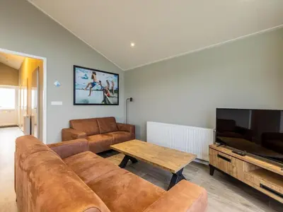 a living room with a couch and a flat screen tv at Karper Vakantiepark De Groote Vliet in Wervershoof