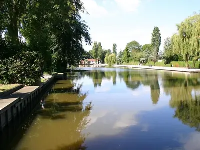 a body of water with trees and a bridge at Karper Vakantiepark De Groote Vliet in Wervershoof