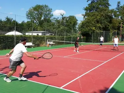 a group of people playing tennis on a tennis court at Karper Vakantiepark De Groote Vliet in Wervershoof