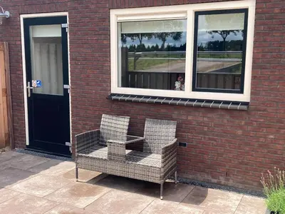 two chairs sitting outside of a building with a window at Boomzicht in Ter Aar