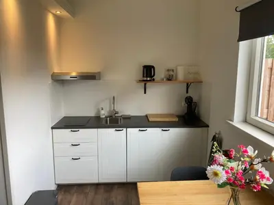a kitchen with white cabinets and a sink and a table at Boomzicht in Ter Aar
