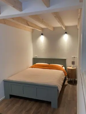 a bedroom with a bed with an orange blanket at Boomzicht in Ter Aar