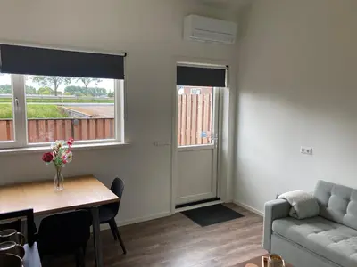 a living room with a couch and a table and two windows at Boomzicht in Ter Aar